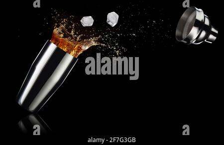 ice cubes and cocktail spilling out of a shaker isolated on black background Stock Photo