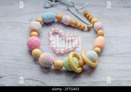 Necklace made from knitted beads and toys for the baby sitting in a sling. Knitted beads. Sling necklace. Stock Photo