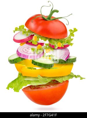 layers of vegetables between a cut tomato flying isolated on white Stock Photo