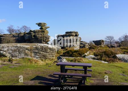 At Brimham Rocks, Nidderdale, there is a long wooden picnic table with stunning rock formations in the distance, Harrogate, North Yorkshire, UK. Stock Photo