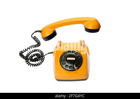 Old, orange rotary dial telephone with hanging receiver, isolated on white background Stock Photo