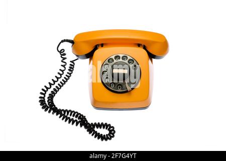 Old, orange rotary dial telephone, isolated on white background. Stock Photo