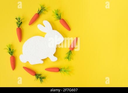 White rabbits and carrots, Easter pattern with bunnie. Minimal Easter background. Spring holidays concept. Yellow background top view mockup Stock Photo