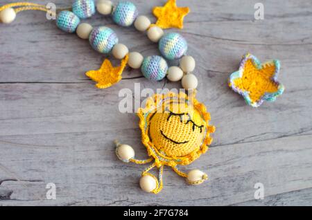 Necklace made from knitted beads and toys for the baby sitting in a sling. Knitted beads. Sling necklace. Stock Photo