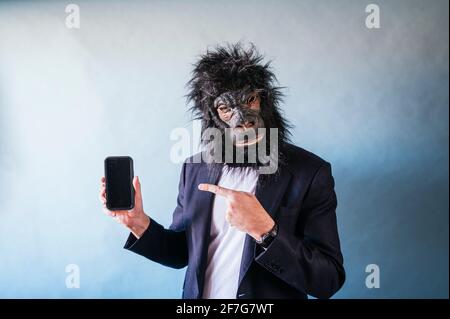 Man with gorilla mask showing smart phone Stock Photo