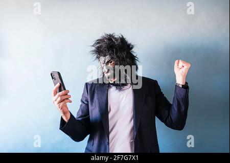 Man in gorilla mask euphoric using smart phone Stock Photo