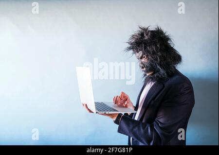 Man with gorilla mask using laptop Stock Photo