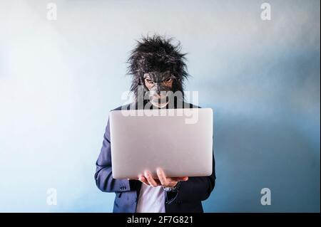 Man with gorilla mask using laptop Stock Photo