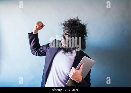 Man in gorilla mask euphoric with laptop under his arm Stock Photo