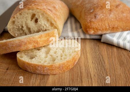 fresh bread slice on chopping board and towel, food close up, delicious homemade sliced italian ciabatta bread on wooden cutting board Stock Photo