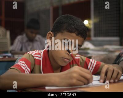 Varanasi, India. 10-16-2019. Portrait of a boy doing his homework before having dinner in the school premises. Stock Photo