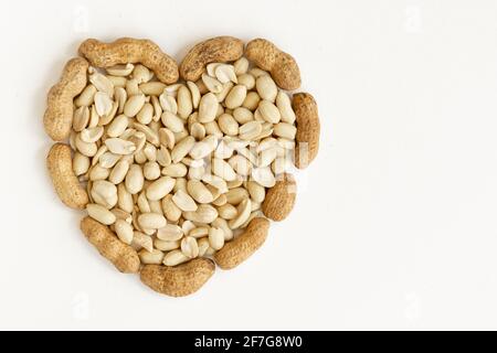 Salted peeled peanuts in a heart shape isolated on white background. Flat lay. From above. Stock Photo