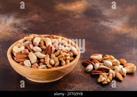 Various Nuts in wooden bowl on dark background. Stock Photo