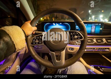 Moscow, Russia - December 24, 2019: The male driver's hand holds the steering wheel of a modern premium SUV Mercedes GLS class. night shooting. driver Stock Photo