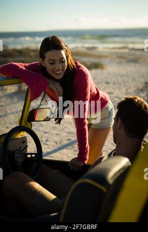 Happy caucasian couple on beach woman leaning on beach buggy man sitting behind steering wheel Stock Photo