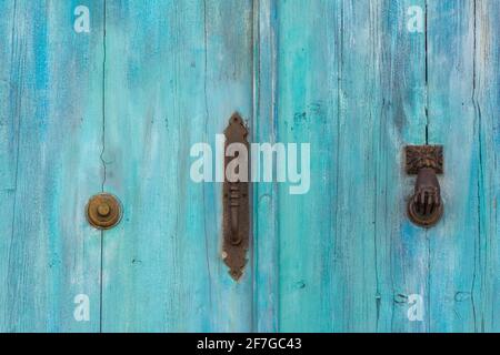 Beautiful door detail with turquoise, aged wood and iron handle, knocker and doorbell Stock Photo