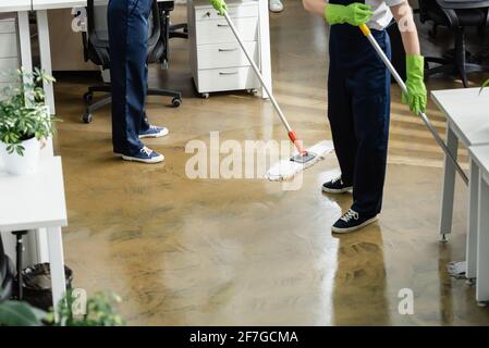Cropped view of cleaners washing floor in office Stock Photo