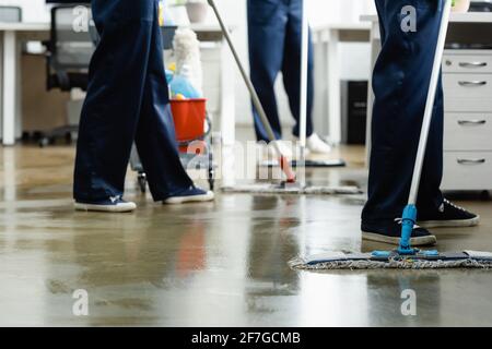 Cropped view of cleaners washing floor with mops in office Stock Photo
