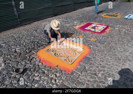 Intricate and vibrant sawdust alfombras decorate the cobblestone streets of Antigua, Guatemala in preparation for the Semana Santa processions. Stock Photo