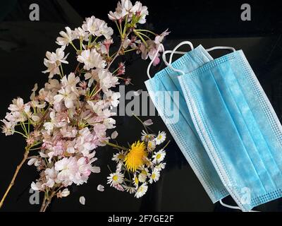Flowers on the side of surgical masks - Covid19 coronavirus concept - Condolence, Grievance, Hope and Solidarity to all the lives lost. Stock Photo