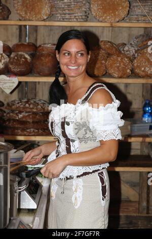Frau mit Tracht  und Dirndl beim Trachtenfest backt Brot am Markt in Brixen in den Dolomiten in Südtirol in Italien Stock Photo