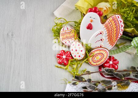 Easter composition of colored gingerbread, eggs, willow branches, flowers and lace doily over light wooden background. Concept of bright spring and happy holidays Stock Photo