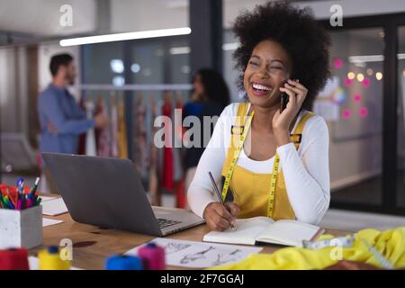 American woman fashion designer wearing tailor's tape measure talking by smartphone smiling Stock Photo