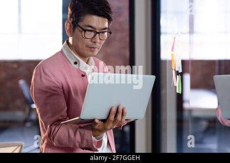 Stylish asian businessman standing and using laptop computer Stock Photo