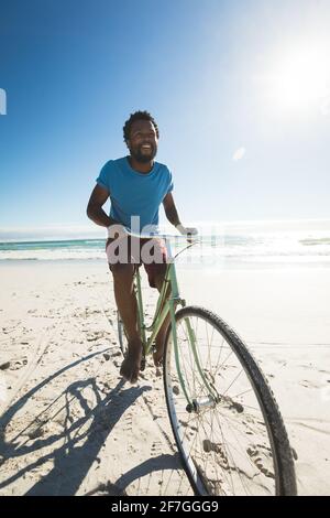 Happy african american man on beach riding bicycle Stock Photo