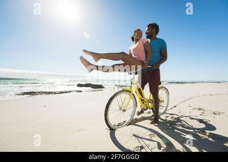 Happy african american couple riding bicycles on the beach Stock Photo