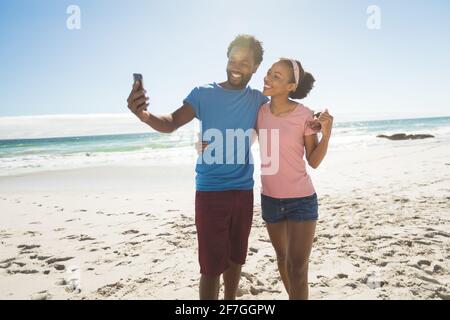 Happy african american couple on beach by the sea taking selfie Stock Photo
