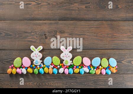 Beautiful flat lay composition of homemade multi colored biscuits on dark wooden background. Easter eggs and rabbits. Top view with space for your greetings Stock Photo