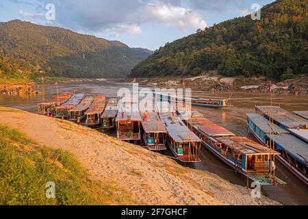 Slowboats / slow boats for river cruises to Luang Phabang / Luang Prabang / Louangphabang on the Mekong River at sunset, Laos Stock Photo