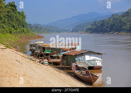 Slowboats / slow boats for river cruises to Luang Phabang / Luang Prabang / Louangphabang on the Mekong River at sunset, Laos Stock Photo