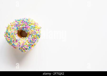 Donut with colorful sprinkles on white background. High angle view with copy space for text. Stock Photo