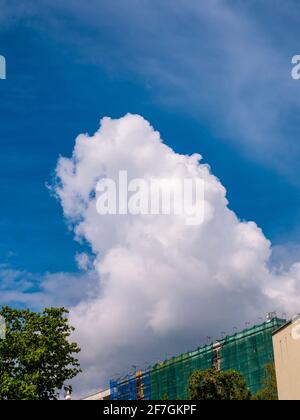 Massive cloud - towering cumulus - forming over building under construction with scaffolds and safety net Stock Photo