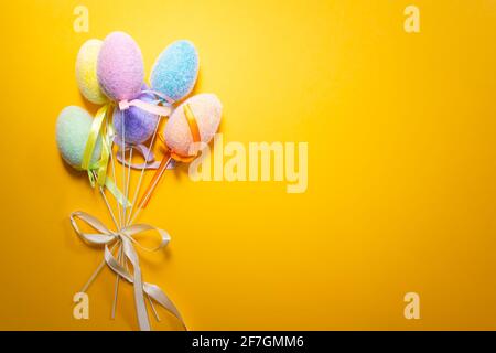 Bouquet of fluffy colorful plastic eggs isolated on yellow background. Easter concept. Stock Photo