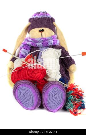 Knitting with spokes. Funny knitted hare purple on a white background. Stock Photo