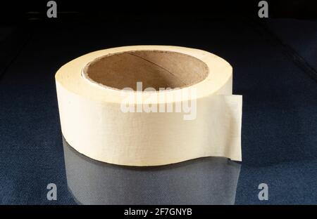 A roll of duct tape made of paper on the table. An object with a reflection on a black background Stock Photo