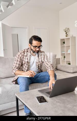 Indian man working or learning online from home office using laptop computer. Stock Photo