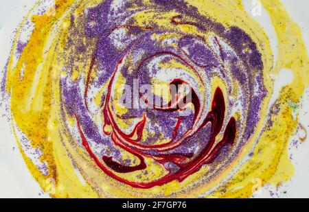 Yellow smeared in a circle with purple sparkles Abstract pattern with curls. Popular fashionable art design. Stock Photo