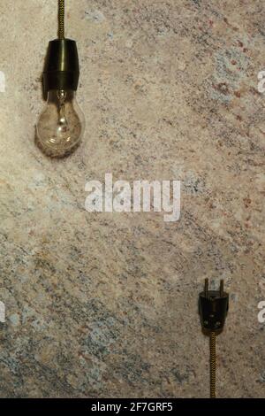 Frame formed by a vintage bulb hanging on a cable and its plug on a marble background. Concept of creativity and thinking. Mockup for innovative ideas Stock Photo