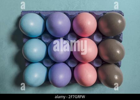 Painted multicolored Easter eggs in pastel gradient shades placed in a purple box on a blue background. Stylish Easter concept Stock Photo
