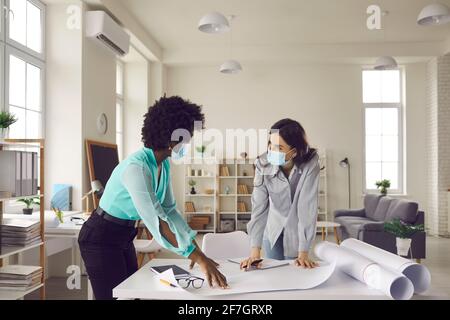 Two creative women wearing face masks working on design project in office studio Stock Photo