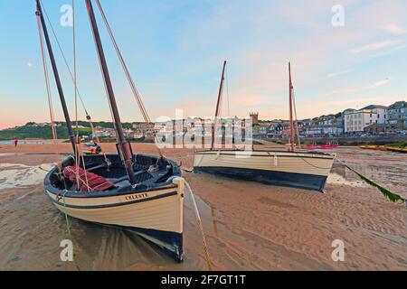 Low tide at St Ives Harbour as the early morning sunlight casts a warm glow over the waterfront Stock Photo