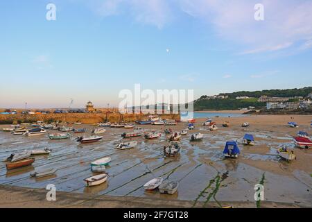 Low tide at St Ives Harbour as the early morning sunlight casts a warm glow over the waterfront Stock Photo