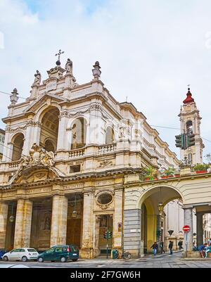 The ornate facade and tall bell tower of Santissima Annunziata Church with stone sculptures and garlands, located in Via Po street, Turin, Italy Stock Photo