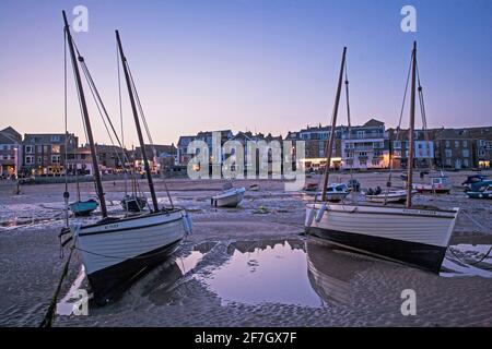 Low tide at St Ives Harbour as the early morning sunlight casts a warm glow over the waterfront Stock Photo