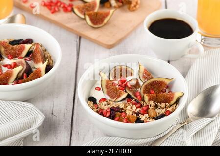 Healthy and delicious breakfast. Oatmeal muesli with Greek yogurt, fresh figs, dried fruits and pomegranate. Stock Photo