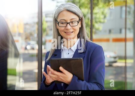 Focused aging lady checking data on her tablet screen Stock Photo